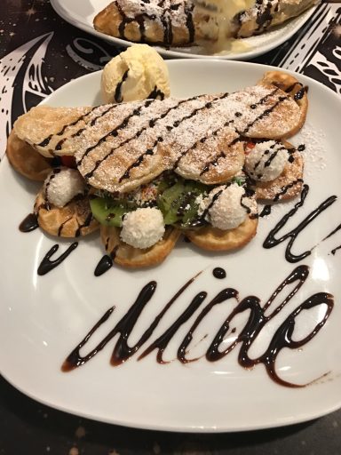 Ein Teller mit einem Dessert aus Waffeln, Eis und Schokoladensauce.